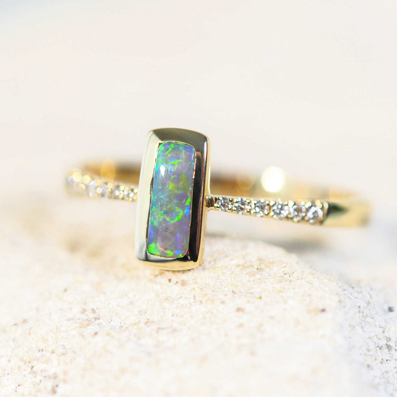 'Ryla' opal ring in 14ct yellow gold featuring a vibrant green rectangular Lightning Ridge semi-black opal, bezel-set and accented with 12 sparkling white diamonds.