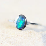 Anneisha handcrafted opal ring with a green Lightning Ridge black opal, bezel-set in 14ct white gold and adorned with two sparkling white diamonds.