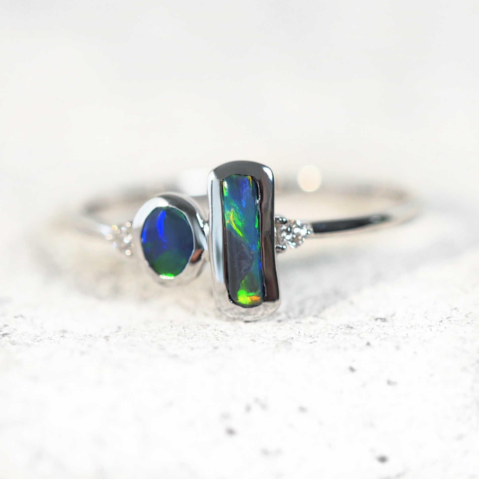 two black opals set into a white gold ring with two diamonds