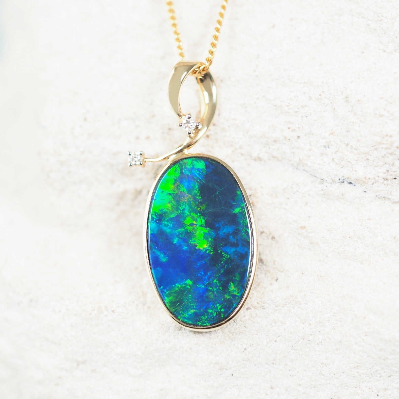 Close-up of 14ct yellow gold opal necklace pendant with two sparkling white diamonds.