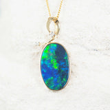 Close-up of 14ct yellow gold opal necklace pendant with two sparkling white diamonds.