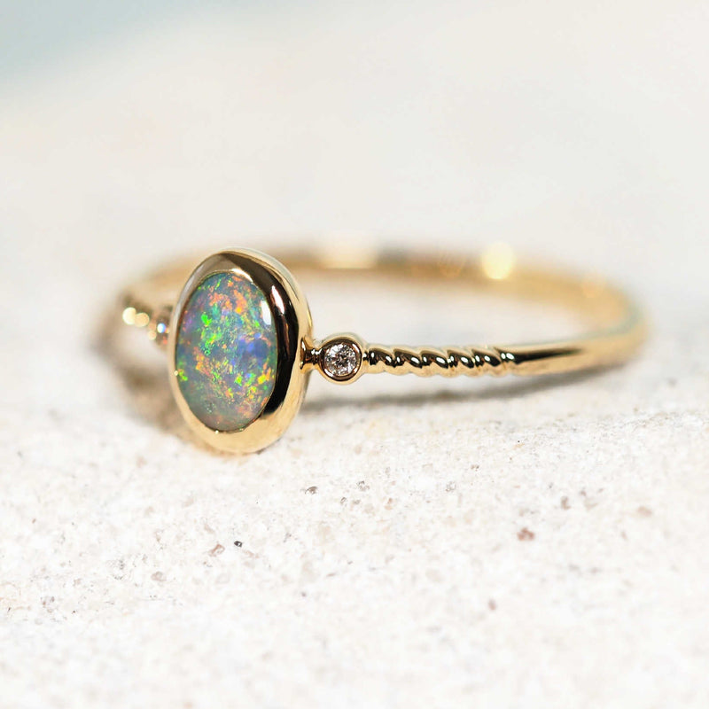 colourful black opal ring set in 14ct yellow gold with two shoulder set diamonds