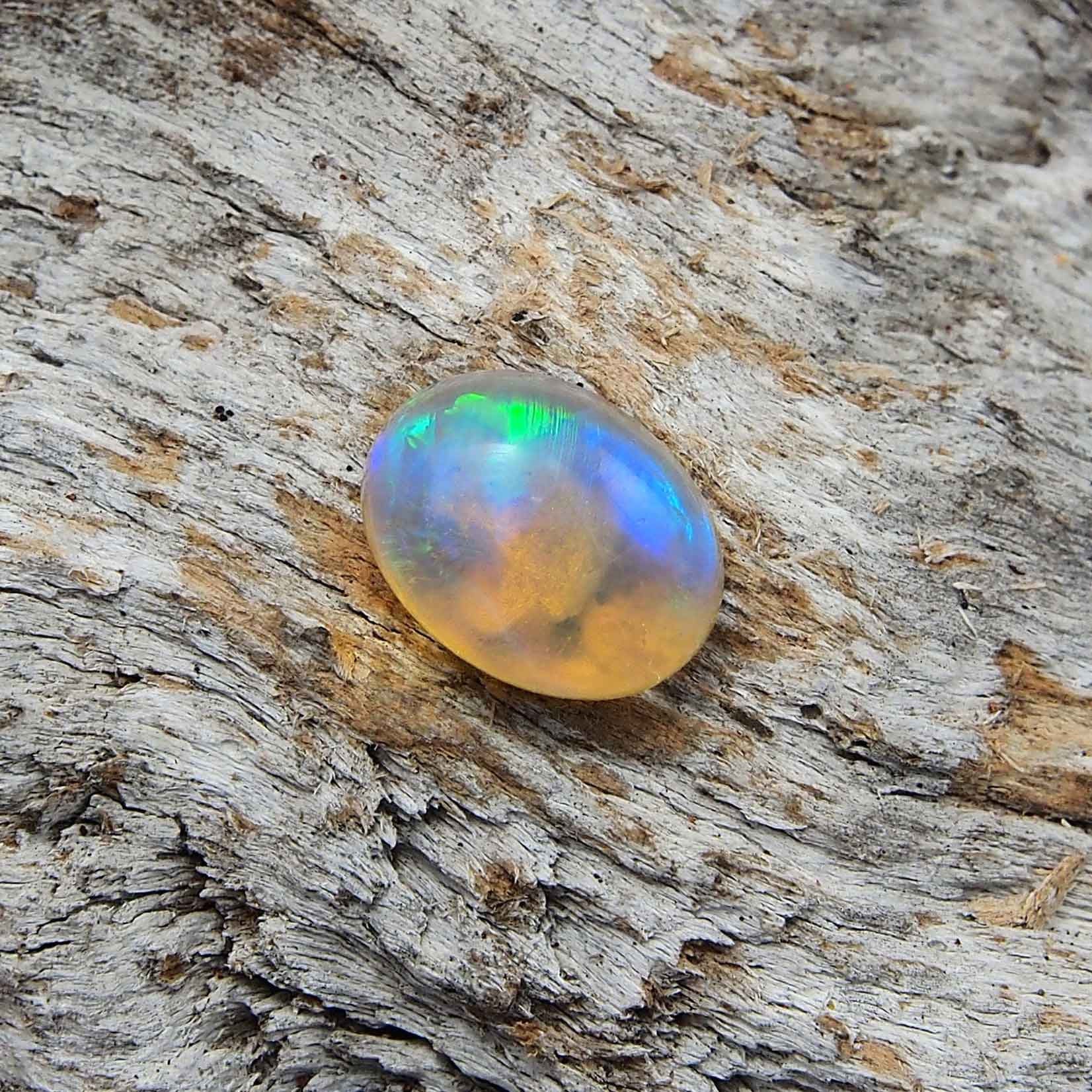 Ethereal rolling flash patterned oval Lightning Ridge solid crystal opal with blue and green highlights, ideal for a ring or necklace pendant setting.