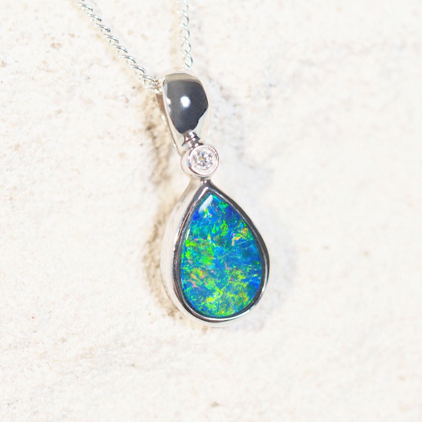 Kamille opal pendant in 14ct white gold featuring a teardrop-shaped Australian doublet opal with vibrant multi-coloured flashes and a sparkling diamond accent.