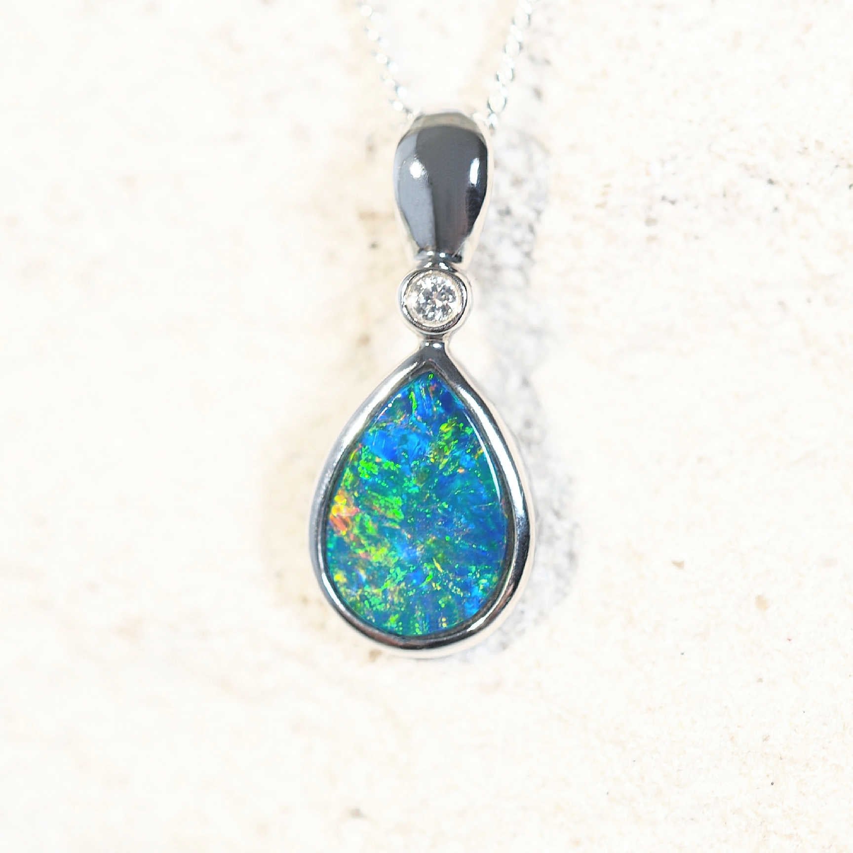 Elegant Kamille opal necklace showcasing a multi-coloured teardrop-shaped Australian doublet opal bezel set in 14ct white gold with a diamond accent.