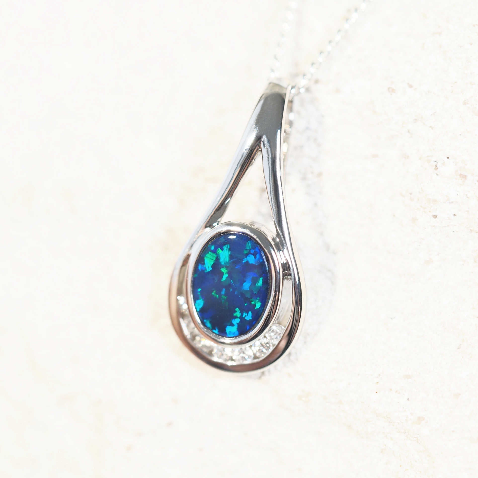 Kimora Ocean opal pendant in 14ct white gold featuring a blue-and-green oval-shaped Australian doublet opal with a red flash and seven sparkling white diamonds.