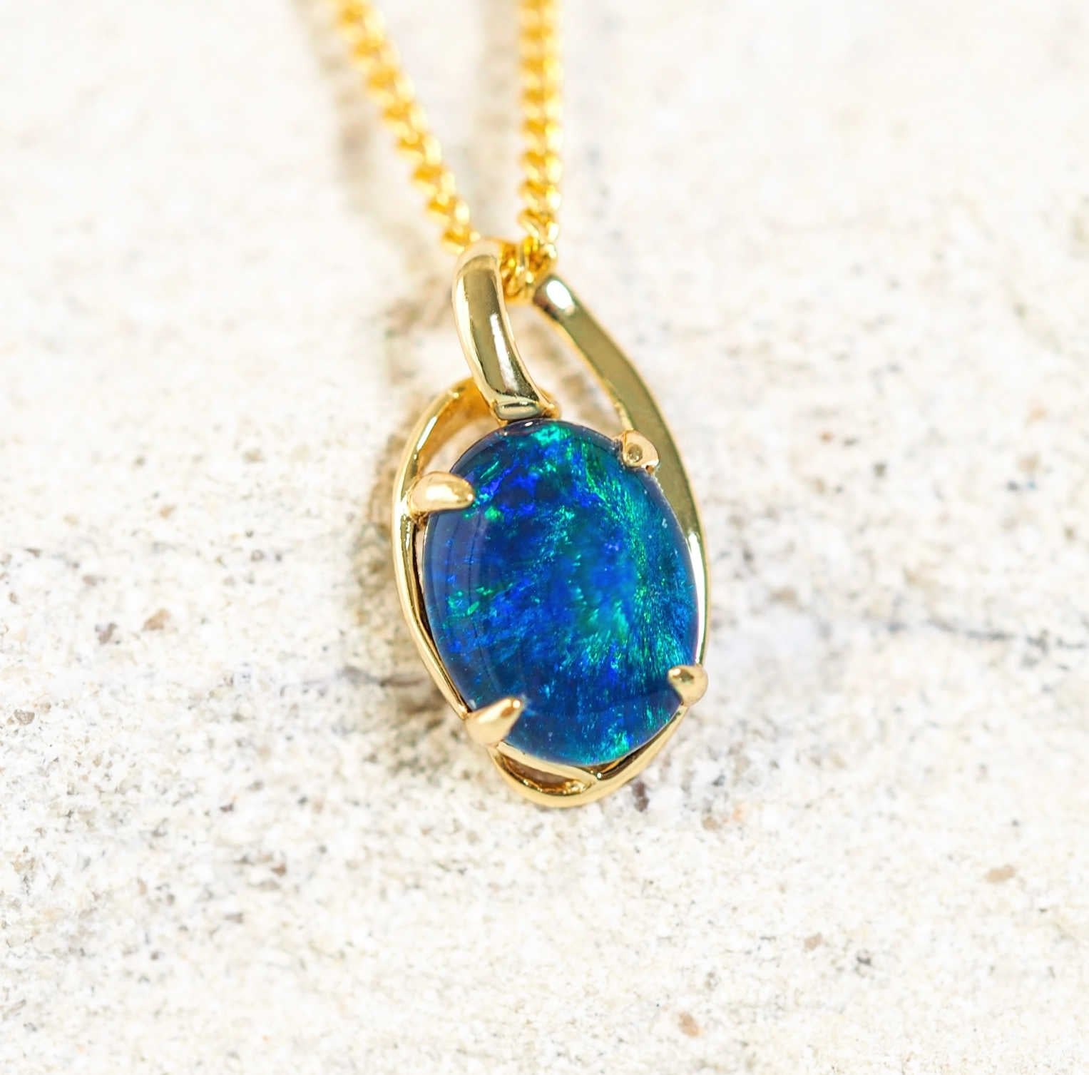 Luxurious gold-plated silver opal necklace pendant, 'Kylan Blue,' with claw-set oval Australian triplet opal in vibrant blue and green tones inspired by the Australian coastline.