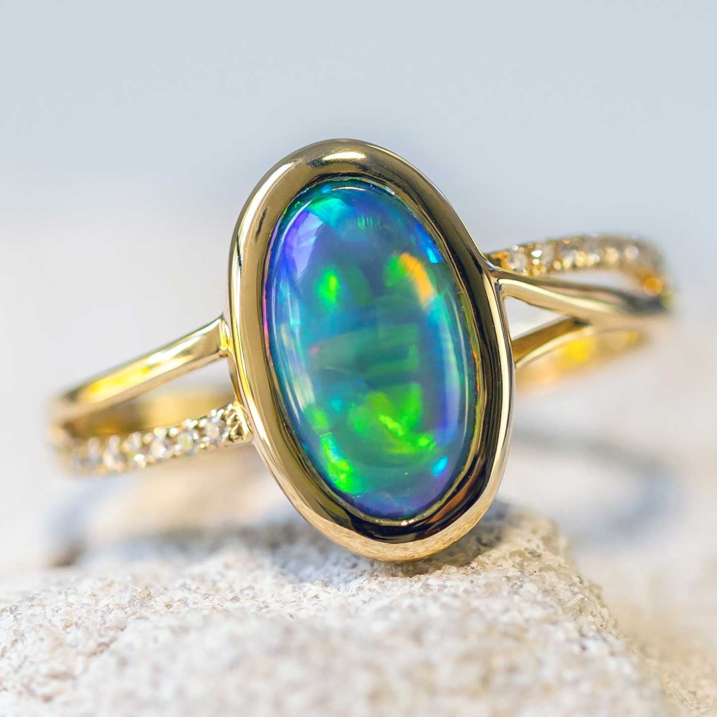 Melia opal ring featuring an 18ct yellow gold split band, oval-shaped Lightning Ridge crystal opal, and 14 white diamond accents