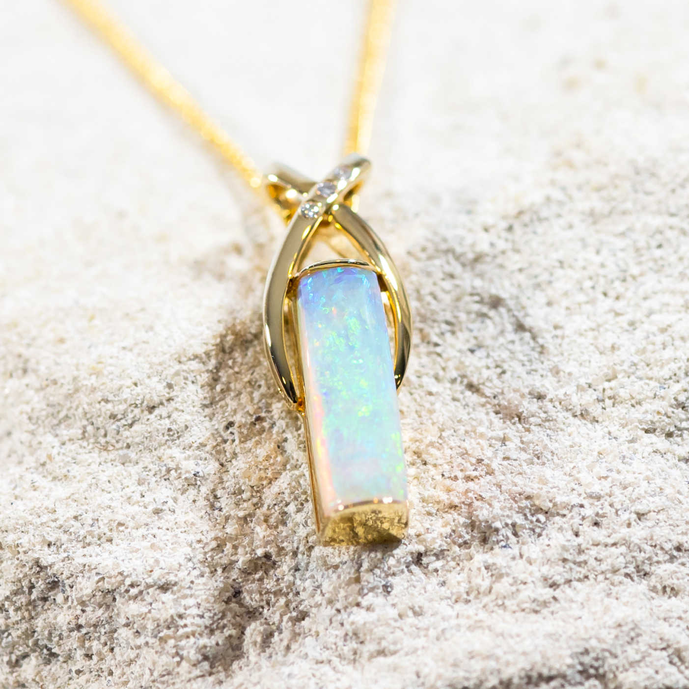 blue and green crystal opal set into a 14ct yellow gold pendant with three diamonds