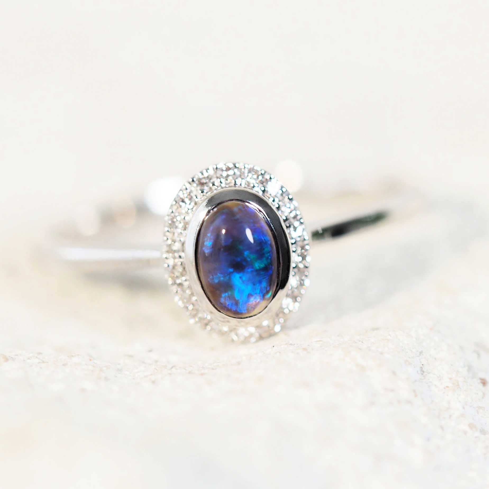 black opal ring set into 14ct white gold surrounded by a halo of diamonds