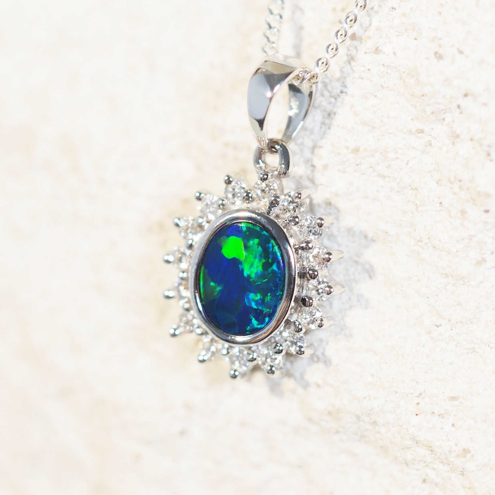 Ocean Princess opal pendant in 18ct white gold with blue-and-green Australian doublet opal surrounded by a halo of sixteen white diamonds.