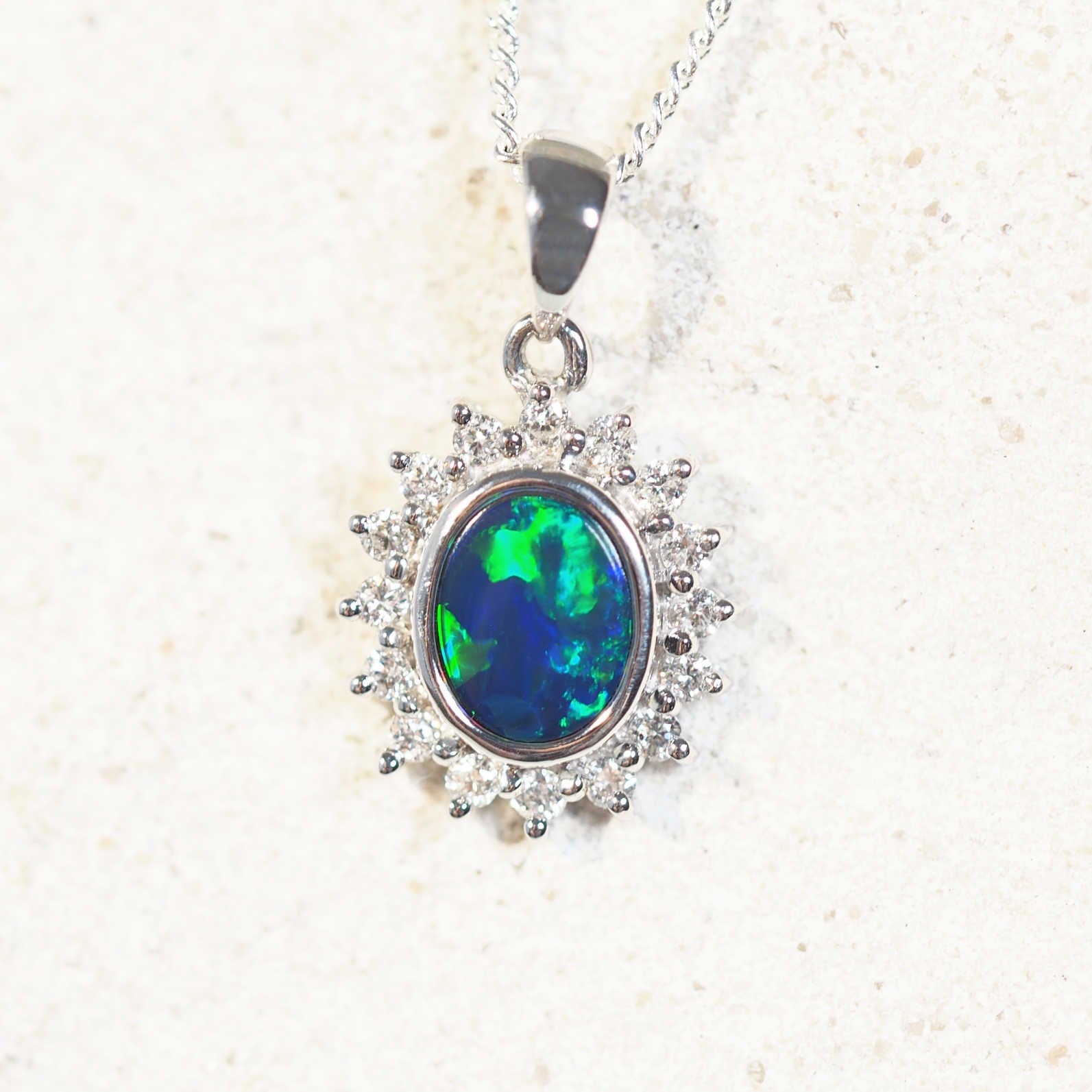 Elegant opal necklace with a stunning blue-and-green oval-shaped Australian doublet opal, bezel set in 18ct white gold with diamond halo."