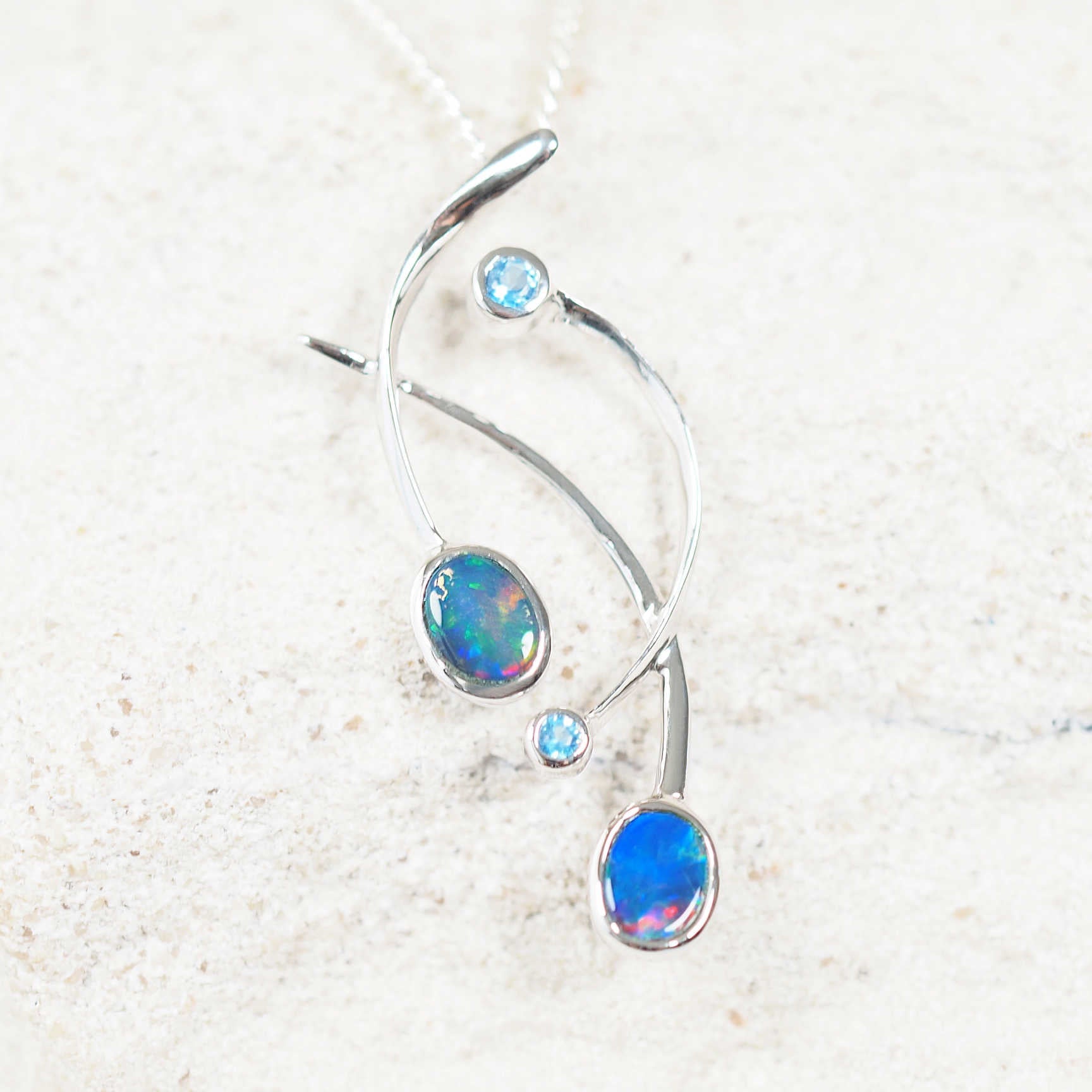 Close-up of the 'Ramina' opal pendant showcasing two oval Australian opals and blue topaz accents in white gold.