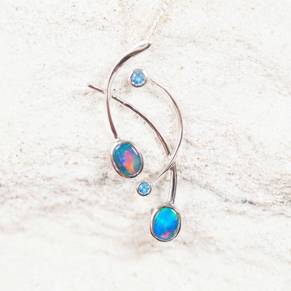 14ct white gold opal pendant featuring two multi-coloured Australian doublet opals and sparkling blue topaz gemstones.