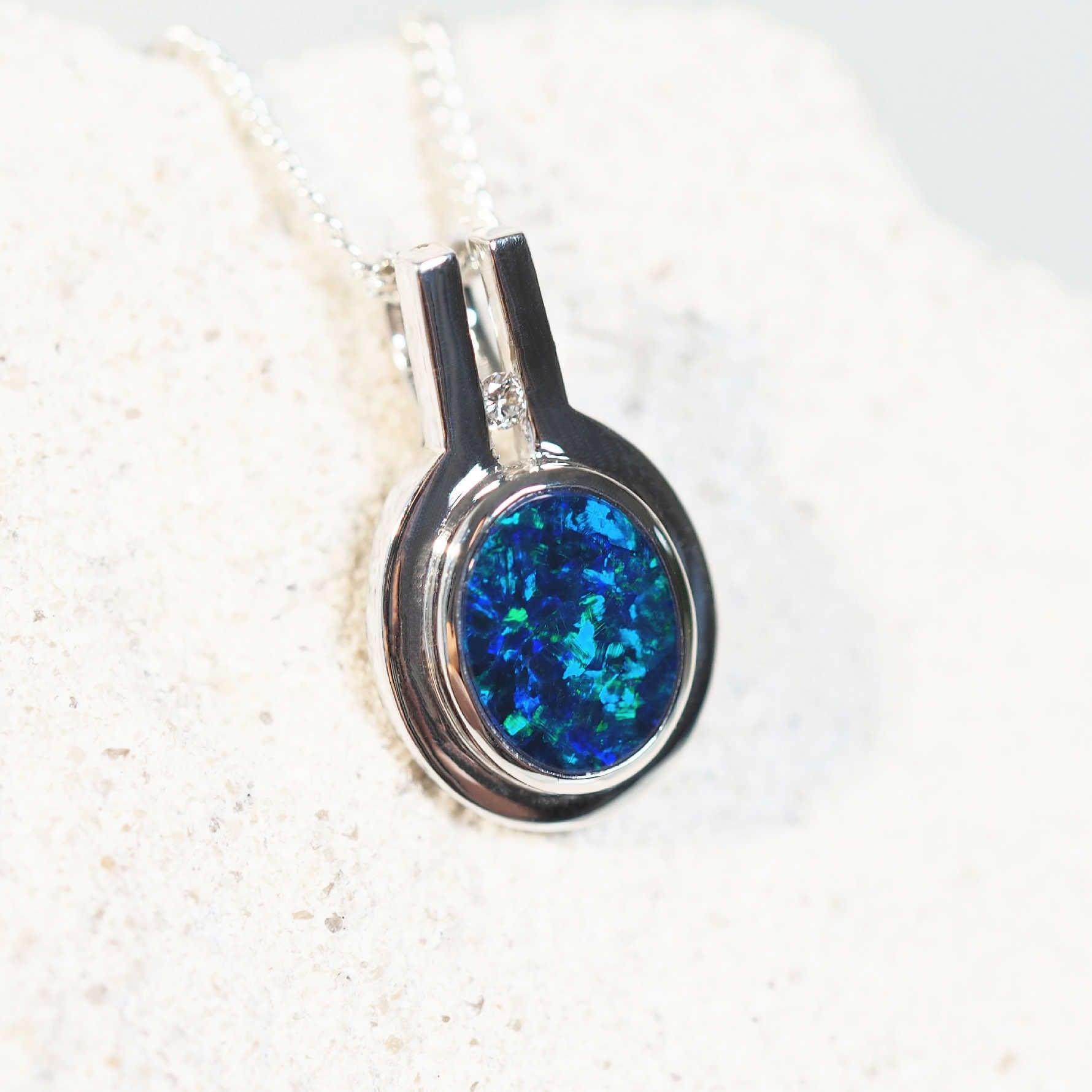 Remi opal pendant in 14ct white gold featuring a vivid blue-and-green oval-shaped Australian doublet opal and a sparkling white diamond accent.