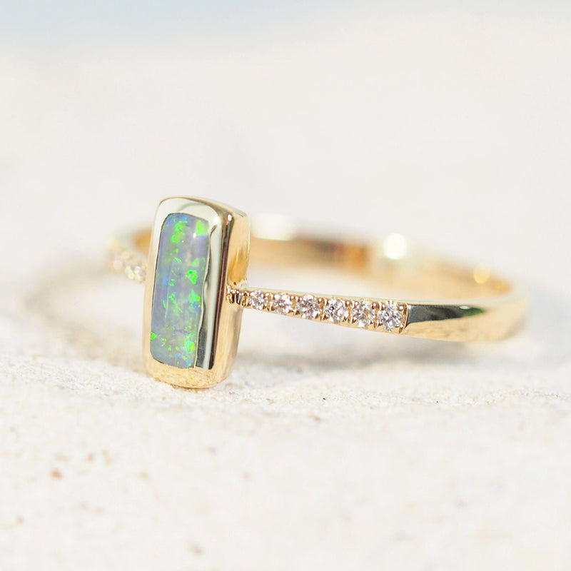 14ct yellow gold Ryla opal ring showcasing a vivid green rectangular Lightning Ridge semi-black opal, securely bezel-set with 12 white diamond accents.