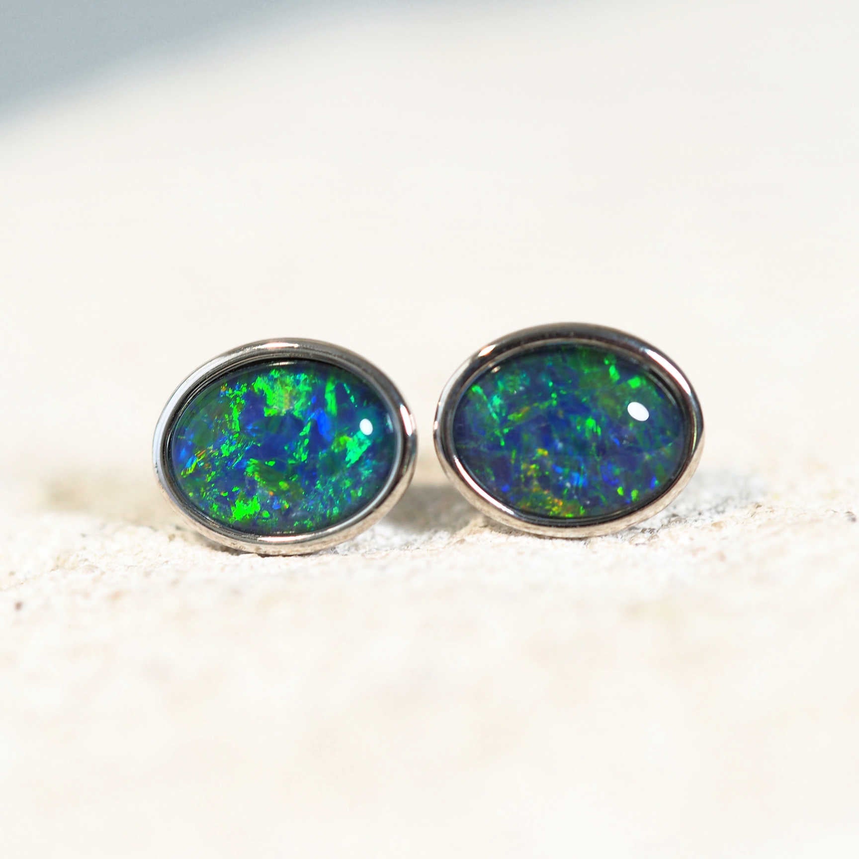 opal stud earrings set with a blue and green triplet opal