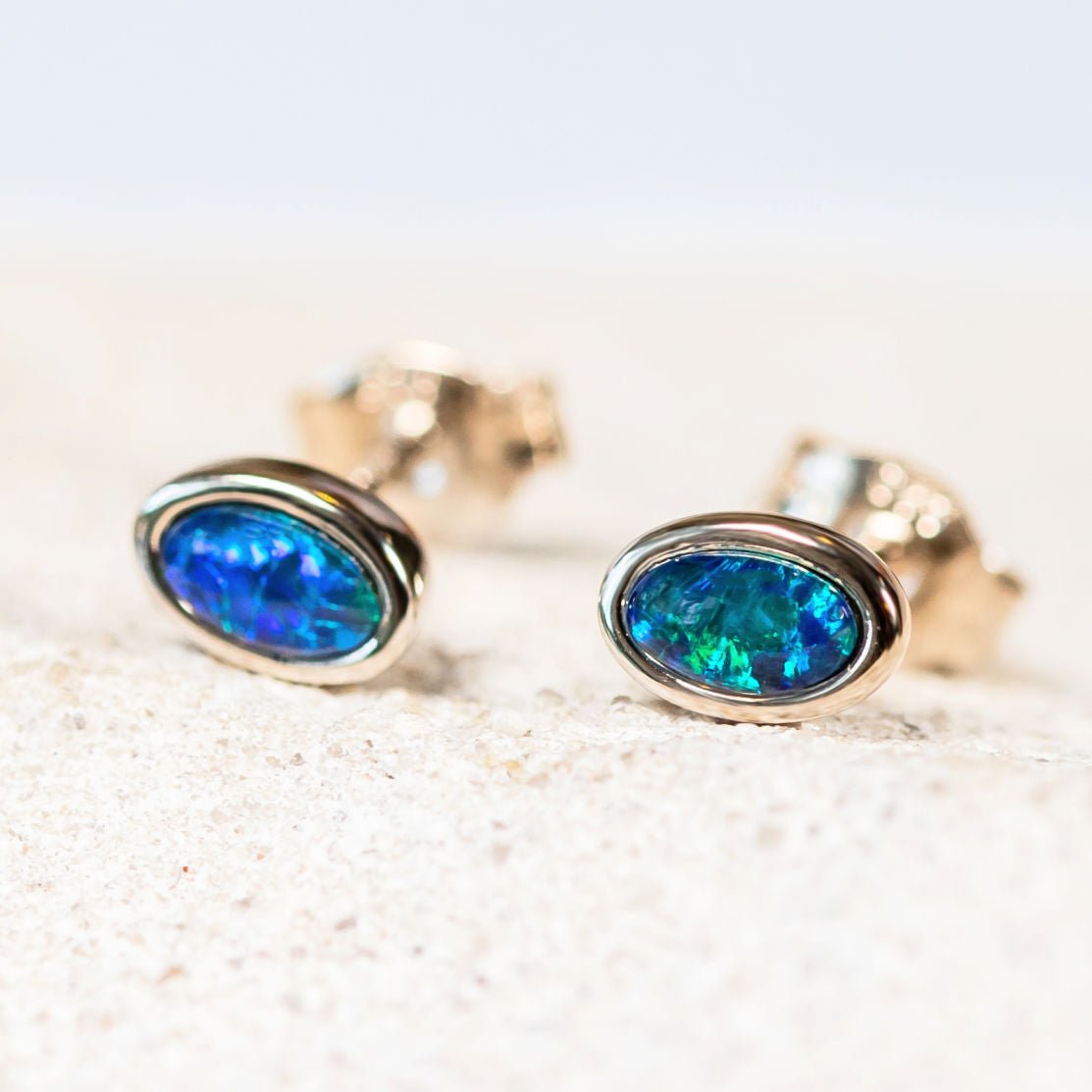 Classic sterling silver stud earrings bezel set with blue and green-coloured oval Australian triplet opals.